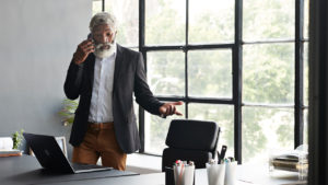 A real estate agent in black suit speaking with his client on phone