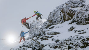 A group of mountaineers climbing mountain and assisting each other.