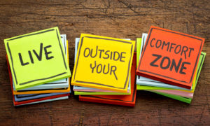 'Live outside your comfort zone' written in black ink on isolated sticky notes