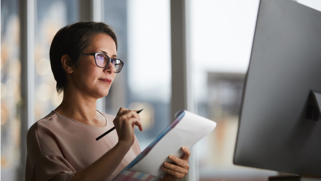 A real estate trainee looking at computer and writing down something