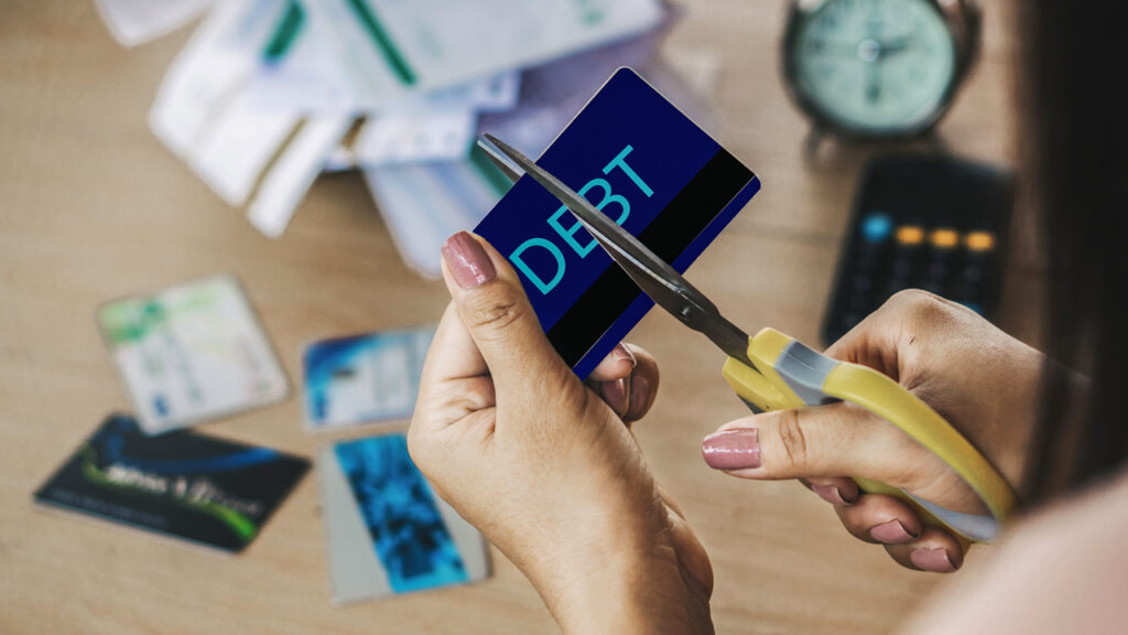 A girl cutting the debt card with scissor