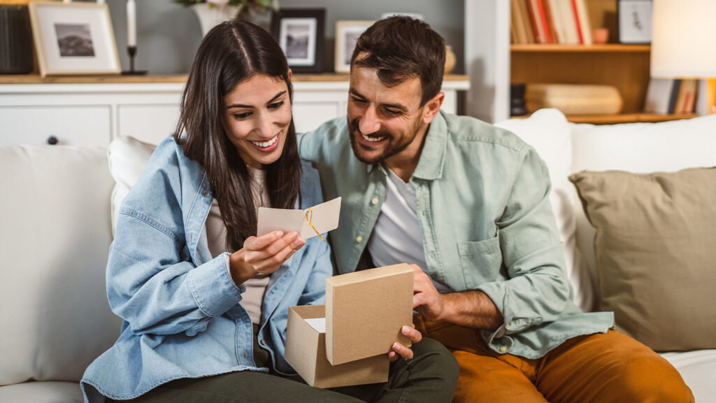 A couple sitting on a looking at a card.