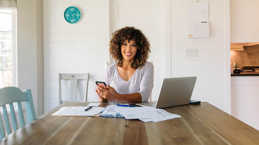 A smiling woman setting and working on a table.